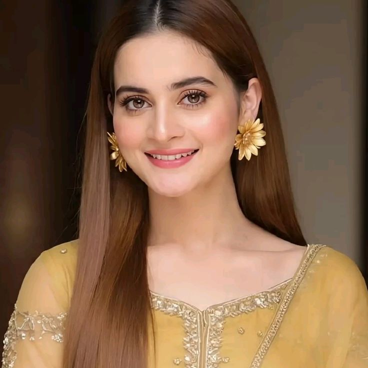 Aiman Khan smiling in yellow embroidered traditional outfit with gold floral statement earrings