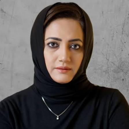  A headshot of Asma Shirazi, a Pakistani journalist, wearing a black hijab and a silver necklace. She is looking directly at the camera with a neutral expression.