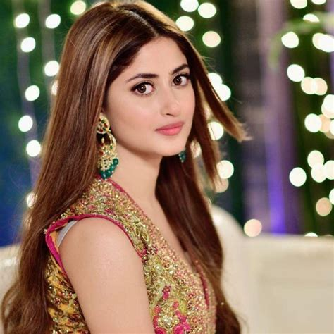 Sajal Aly in a traditional embellished outfit with festive lighting in the background