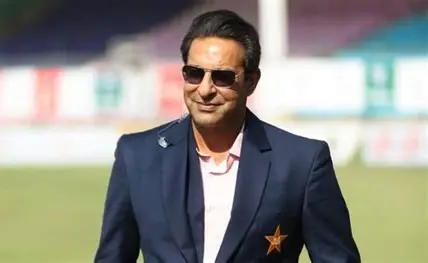 Wasim Akram wearing a navy blue blazer with Pakistan cricket star emblem
