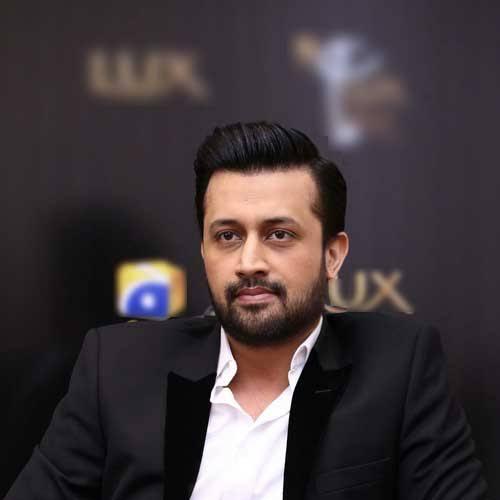 A portrait of Pakistani singer Atif Aslam in a black suit with a white shirt, looking directly at the camera.