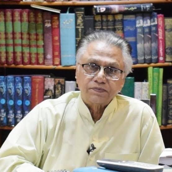 A portrait of Pakistani journalist and political analyst Hassan Nisar, wearing glasses and a light-colored shirt, sitting in front of a bookshelf.