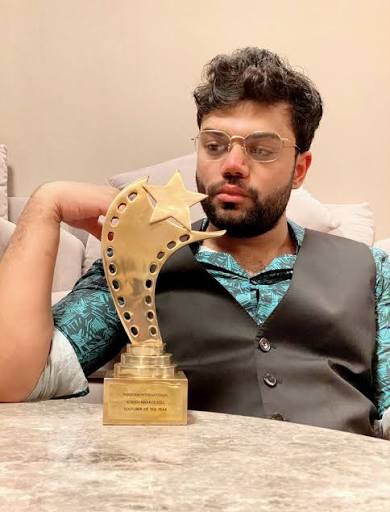 Ducky Bhai sitting near an award