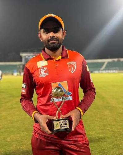 Babar Azam wearing red holding a trophy