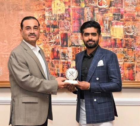 Babar Azam receiving an award while wearing a blue coat