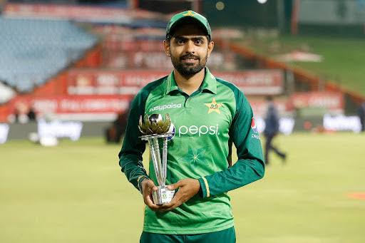 Babar Azam wearing blue holding a trophy