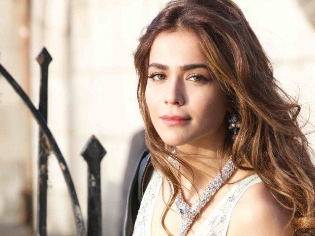 A close-up portrait of Pakistani actress Humaima Malick, with long brown hair and a white and silver necklace, looking directly at the camera.
