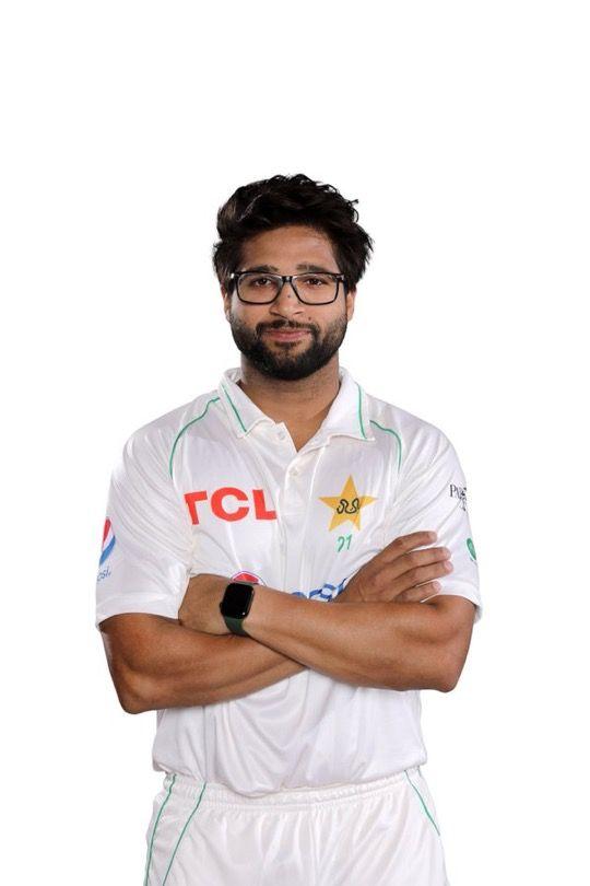 Imam-ul-Haq standing with arms crossed wearing Pakistan’s white Test cricket uniform and glasses against a white background