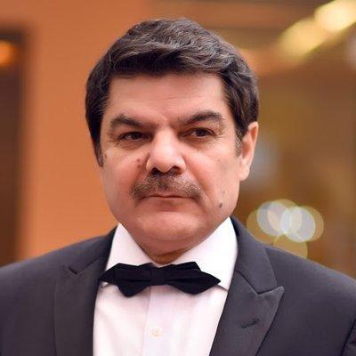A portrait of Pakistani journalist and television host Mubashir Luqman wearing a tuxedo and bow tie.