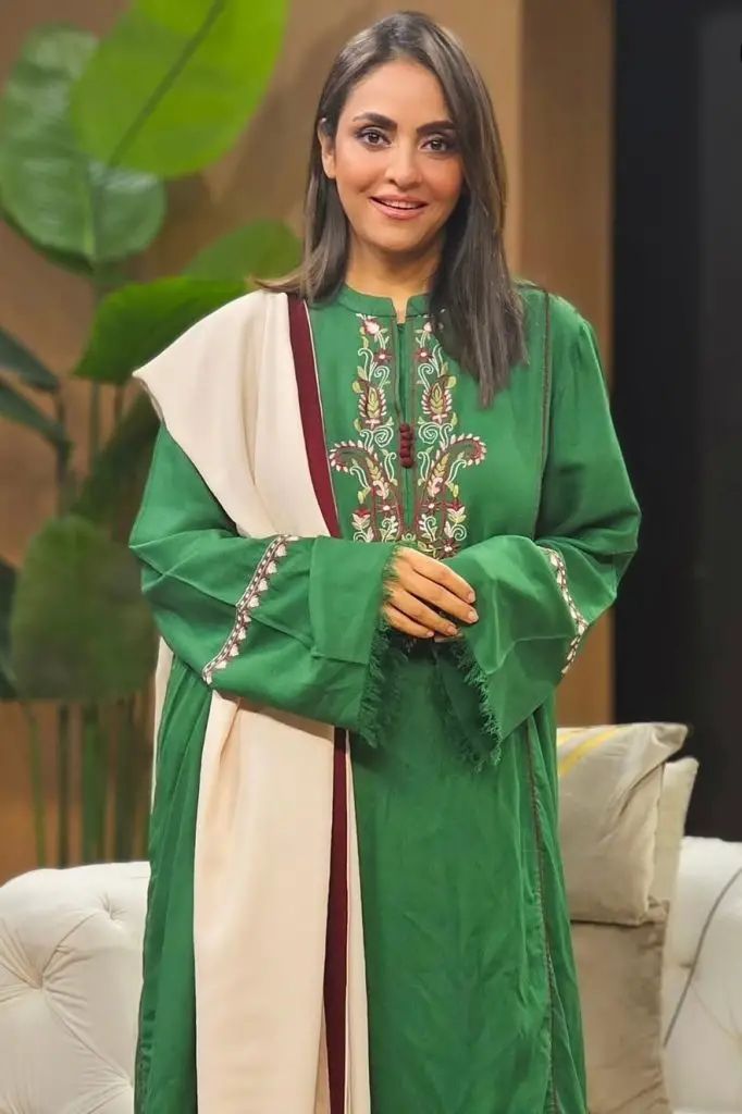 Nadia Khan wearing emerald green traditional outfit with gold embroidery on television show set
