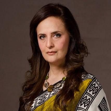 A portrait of Pakistani actress Hina Khawaja Bayat, who is wearing a yellow and black patterned scarf and a beaded necklace. She has long, dark brown hair and is looking directly at the camera.
