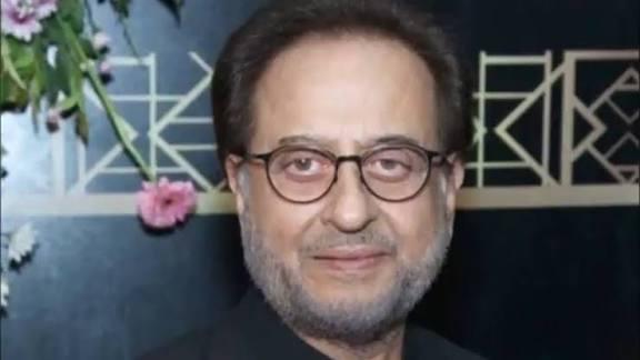 A close-up portrait of Pakistani actor Nadeem Baig, who is wearing glasses and a black shirt.
