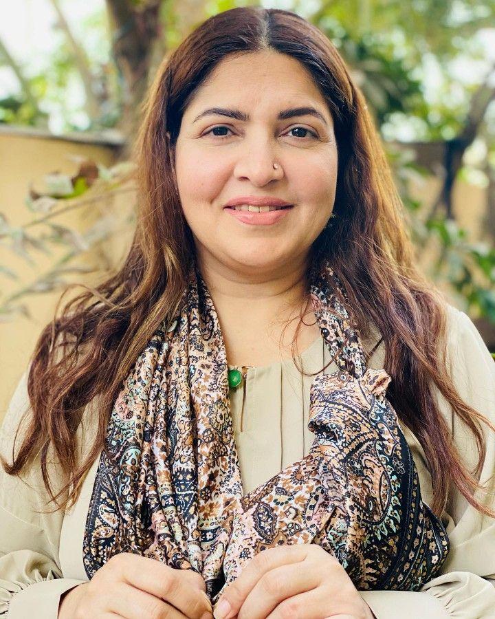 “Shugufta Ijaz smiling in a beige outfit with printed dupatta and nose ring, photographed outdoors”