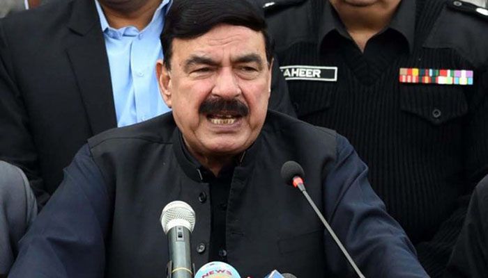 Sheikh Rasheed Ahmad speaking at press conference with microphones in black traditional waistcoat