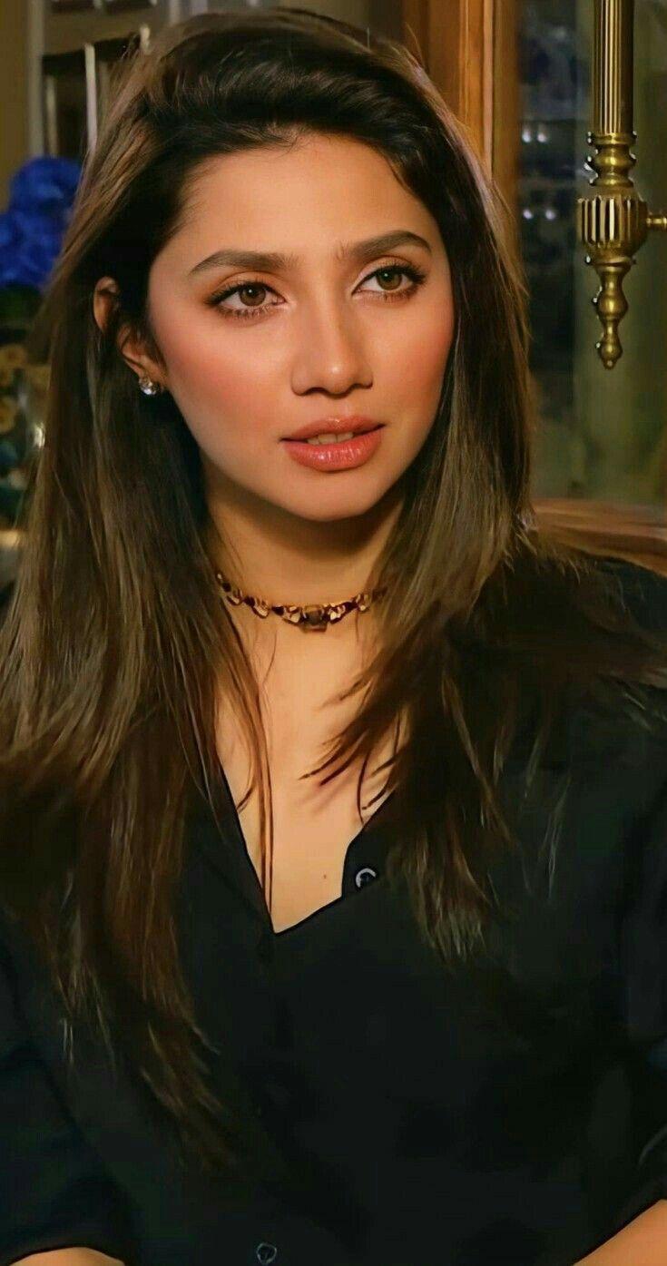 A close-up portrait of Pakistani actress Mahira Khan, with long brown hair, wearing a black shirt and a choker necklace.