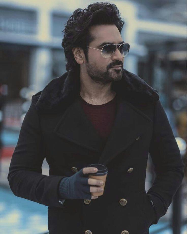 A close-up portrait of Pakistani actor Humayun Saeed, looking to his right, wearing sunglasses and a dark coat, with a beard and styled hair.