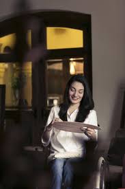 Muniba Mazari receiving an award on stage, seated in a wheelchair, smiling confidently while holding a trophy, dressed in elegant traditional attire.