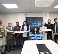 Muniba Mazari receiving an award on stage, seated in a wheelchair, smiling confidently while holding a trophy, dressed in elegant traditional attire.